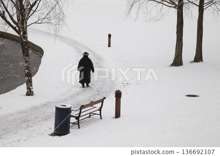 Older woman walking in a park in winter Older woman walking in a park in winter 136692107