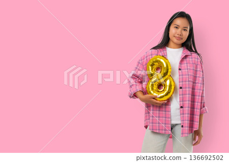 Young woman holds a golden balloon number 8 in spring 136692502