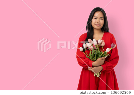Young woman holds flowers in a colorful setting for celebration Young woman holds flowers in a colorful setting for celebration 136692509