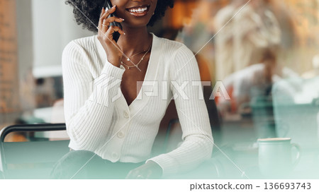 Woman talking on mobile phone in a cafe during afternoon hours with people in the background Woman talking on mobile phone in a cafe during afternoon hours with people in the background 136693743