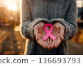 woman holding pink cancer awareness ribbon in warm sunlight background. 136693793