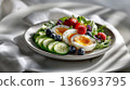 Fresh salad with halved cherry tomatoes, green peas, shredded chicken, red onion, leafy greens, topped with a perfectly cooked soft boiled egg seasoned with black pepper. 136693795