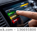 Finger taps car touchscreen driving mode menu showing ECO COMFORT SPORT, offering choice between efficiency, comfort and sport. 136693800