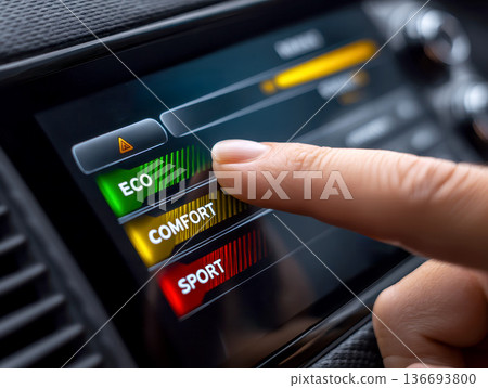 Finger taps car touchscreen driving mode menu showing ECO COMFORT SPORT, offering choice between efficiency, comfort and sport. 136693800