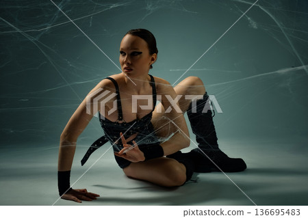 Woman in black gothic attire posing dynamically while tangled in spiderwebs. 136695483