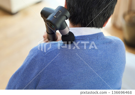 亞洲老年男子用按摩槍按摩肩膀 136696468