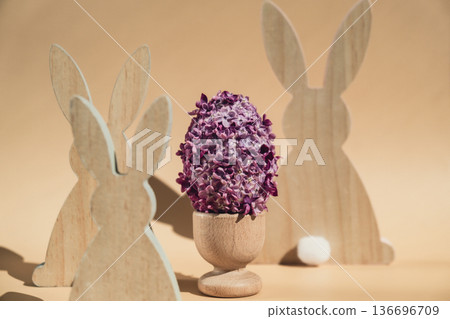 Creative Easter egg shape made of lilac spring petals flowers. Eco-friendly wooden bunnies decoration. Minimal holiday concept still life. Copy space greeting card Creative Easter egg shape made of lilac spring petals flowers. Eco-friendly wooden bunnies decoration. Minimal holiday concept still life. Copy space greeting card 136696709