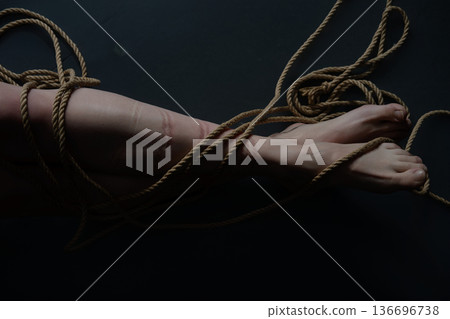 Ropes create patterns on skin during shibari practice with a woman engaged in BDSM activity 136696738