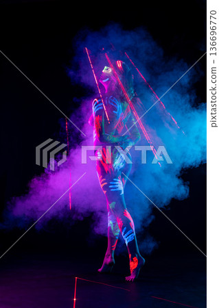 Woman body with neon handprint paint art in futuristic UV blacklight and smoke Woman body with neon handprint paint art in futuristic UV blacklight and smoke 136696770