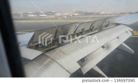 Airplane wing with extended flaps during takeoff on runway 136697090