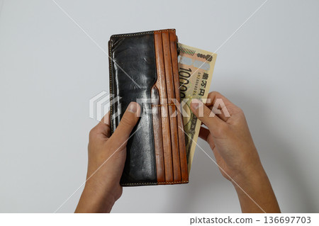 一個人從錢包裡掏出一張10000日圓的鈔票。 136697703