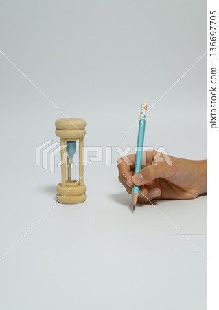 A child's hands studying by measuring time with an hourglass 136697705