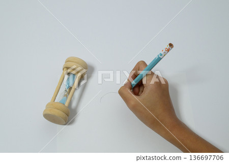 A bird's-eye view of a child studying by tilting an hourglass 136697706