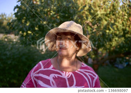 a senior woman in pink dress and straw hat enjoying golden hour sunset in the garden a senior woman in pink dress and straw hat enjoying golden hour sunset in the garden 136698097