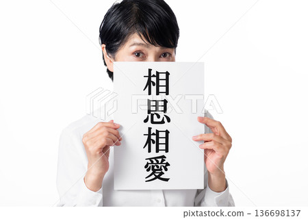 一位靦腆的老婦人雙手拿著一張紙，上面寫著「互相愛慕」幾個字。 136698137