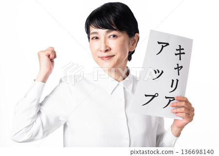 A senior woman wearing a white shirt holding a paper with the words "Career Advancement" written on it and making a fist pump A senior woman wearing a white shirt holding a paper with the words "Career Advancement" written on it and making a fist pump 136698140