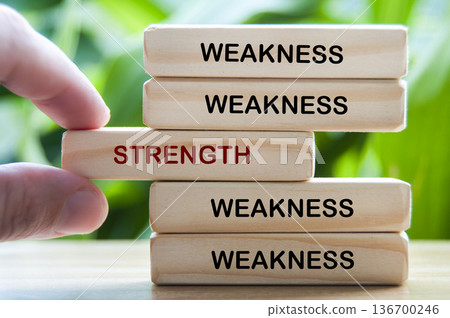 Weakness and Strength text on wooden blocks representing transforming weakness into strength through self improvement 136700246