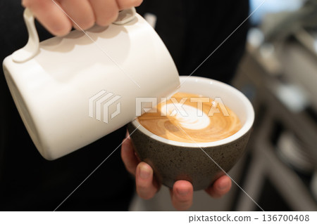 女人的手正在倒一杯拿鐵咖啡 136700408
