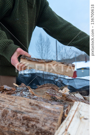 Stacking Firewood Outdoors in Snowy Countryside. 136700618