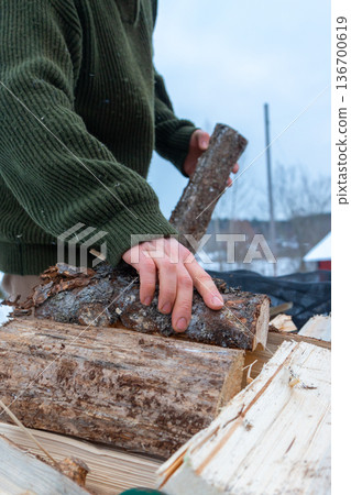 Stacking Firewood Outdoors in Snowy Countryside. 136700619