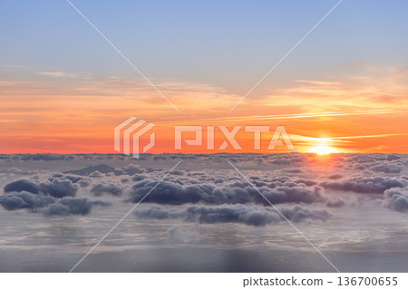 Sunrise above a vast sea of clouds over the Atlantic, soft orange light spreads across calm water 136700655