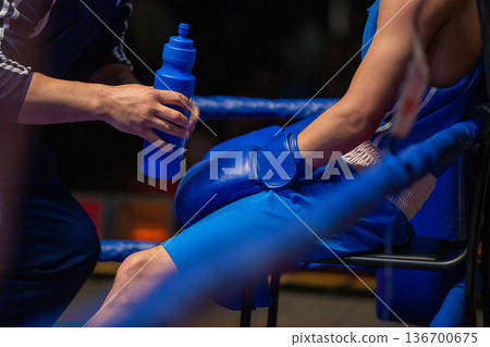 Corner man giving bottle water to boxer Corner man giving bottle water to boxer 136700675