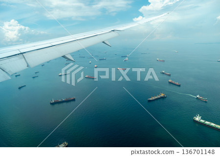 Airplane arriving over sea with cargo ships in Singapore 136701148