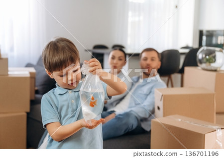Child is standing and holding fish. Family of husband, wife and son are moving into new house Child is standing and holding fish. Family of husband, wife and son are moving into new house 136701196