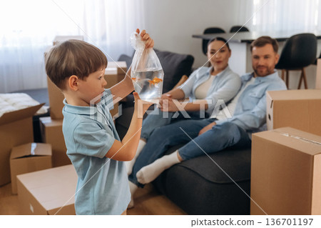 Child is standing and holding fish. Family of husband, wife and son are moving into new house Child is standing and holding fish. Family of husband, wife and son are moving into new house 136701197