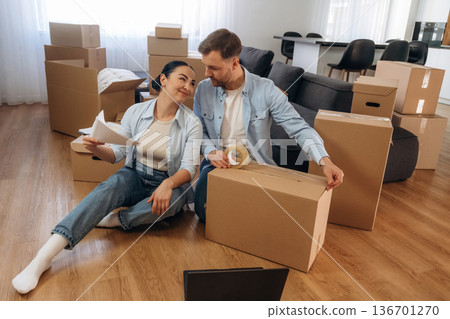 Packing the box, using scotch. Happy couple moved into new house Packing the box, using scotch. Happy couple moved into new house 136701270