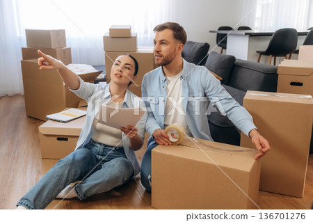 Woman is with documents, man is packing the box. Happy couple moved into new house 136701276