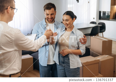 Receiving keys. Couple are buying new house with the help of manager Receiving keys. Couple are buying new house with the help of manager 136701337