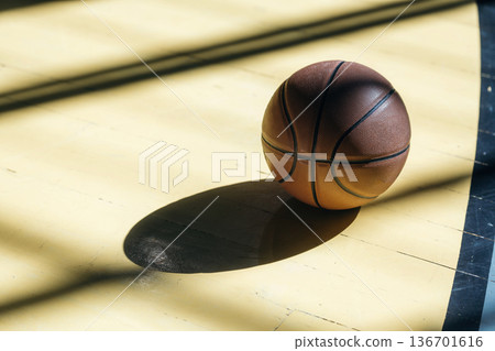 Close up view of basketball ball that is on the ground indoors under sunlight 136701616