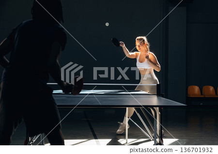 Playing against each other. Tennis game, man and woman are indoors Playing against each other. Tennis game, man and woman are indoors 136701932