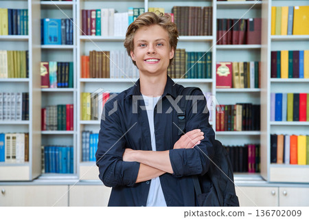 Portrait of smiling teenage student with crossed arms in classroom library Portrait of smiling teenage student with crossed arms in classroom library 136702009