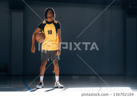 Relaxed, standing and posing. Young black man is playing basketball indoors Relaxed, standing and posing. Young black man is playing basketball indoors 136702184