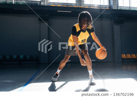 Practicing indoors. Young black man is playing basketball 136702196