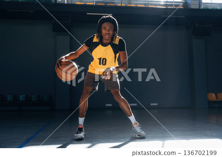 Practicing indoors. Young black man is playing basketball 136702199