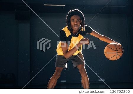 Practicing indoors. Young black man is playing basketball 136702200