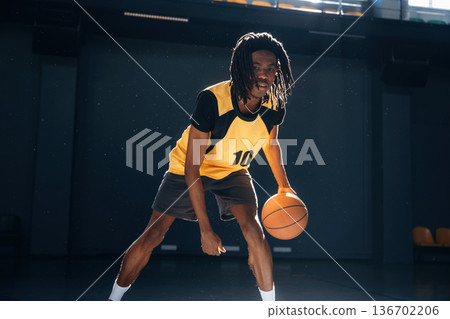 Playing basketball. Young black man is indoors Playing basketball. Young black man is indoors 136702206