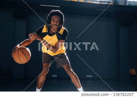 Playing basketball. Young black man is indoors Playing basketball. Young black man is indoors 136702207