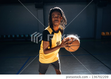 Playing basketball. Young black man is indoors Playing basketball. Young black man is indoors 136702209