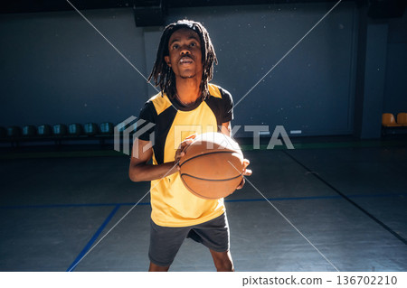 Playing basketball. Young black man is indoors Playing basketball. Young black man is indoors 136702210