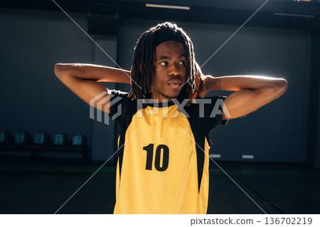 Ball is behind neck. Young black man is playing basketball indoors 136702219