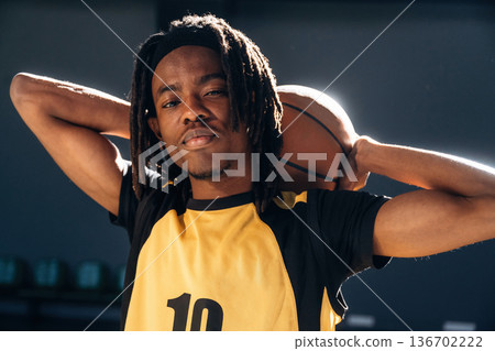 Ball is behind neck. Young black man is playing basketball indoors 136702222