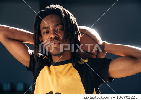 Ball is behind neck. Young black man is playing basketball indoors 136702223