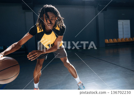 Leading the ball forward. Young black man is playing basketball indoors 136702230