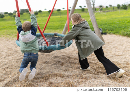 Children playing on nest swing in park Children playing on nest swing in park 136702506
