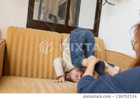 Child playing upside down on couch with adult Child playing upside down on couch with adult 136702514