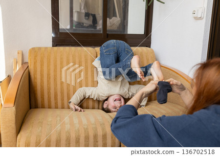 Child having fun on couch getting dressed by adult Child having fun on couch getting dressed by adult 136702518